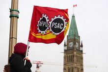 A PSAC worker holds a flag on a picket line in Ottawa, Wednesday, April 19, 2023. Canada's largest federal public-service union and the federal government remain at the bargaining table as workers strike and service disruptions begin to be felt across the country. THE CANADIAN PRESS/Sean Kilpatrick
