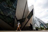 A person wearing a mask walks by the Royal Ontario Museum in Toronto, on Friday, June 26, 2020. THE CANADIAN PRESS/Cole Burston