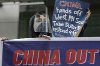 Protesters hold slogans during a rally outside the Chinese consulate in Manila, Philippines on May 7, 2021. The Philippine military defiantly redeployed two supply boats on Monday, Nov. 22, 2021 to provide food to Filipino marines guarding a disputed shoal in the South China Sea after the Chinese coast guard used water cannons to forcibly turn the boats away in an assault last week that drew angry condemnation and warnings from Manila. (AP Photo/Aaron Favila, File)