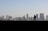 FILE PHOTO: A man walks along a wall overlooking the central Mumbai's financial district skyline, India, March 9, 2017. REUTERS/Danish Siddiqui