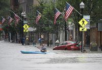 A kayaker paddles across Main Street in downtown Barre, Vt., on Monday night, July 10, 2023. (Jeb Wallace-Brodeur/The Times Argus via AP)