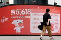 FILE PHOTO: A resident, wearing a face mask following the coronavirus disease (COVID-19) outbreak, walks past a JD.com advertisement for the "618" shopping festival displayed outside a shopping mall in Beijing, China June 14, 2022. REUTERS/Carlos Garcia Rawlins/File Photo
