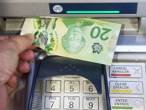 As the federal government pushes to reduce bank fees, a report from an economist figures Canadians are overpaying by more than $7.7 billion a year. Money is removed from an ATM in Montreal, Monday, May 30, 2016. THE CANADIAN PRESS/Ryan Remiorz