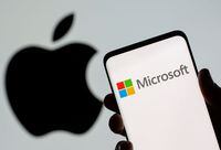 Microsoft logo is seen on the smartphone in front of displayed Apple logo in this illustration taken, July 26, 2021.