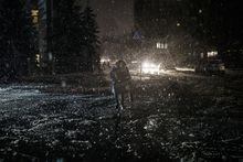 A woman crosses the street during snowfall, as power outages continue in Kyiv, Ukraine, Friday, Dec. 16, 2022. Ukrainian authorities reported explosions in at least three cities Friday, saying Russia has launched a major missile attack on energy facilities and infrastructure. (AP Photo/Felipe Dana)