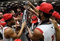 Carleton Ravens players reach for the trophy as they celebrate their win over the Dalhousie Tigers in men's championship final basketball game of the U Sports Final 8 Championships, in Ottawa, on Sunday, March 8, 2020.