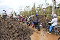 Motorists make their way through boulders washed from nearby Mayon volcano along a damaged road  after super Typhoon Goni hit the town of Malilipot, Albay province, south of Manila on November 1, 2020. - At least seven people were killed as Typhoon Goni pounded the Philippines on November 1, ripping off roofs, toppling power lines and causing flooding in the hardest-hit areas where hundreds of thousands have fled their homes. (Photo by Charism SAYAT / AFP) (Photo by CHARISM SAYAT/AFP via Getty Images)