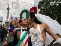FILE - In this Sept. 24, 2016 file photo, demonstrators dressed as a bride and groom marching against homophobia, kiss as they arrive at the Angel of Independence monument, in Mexico City. Mexico’s foreign affairs secretary has instructed the country’s consulates throughout the world to allow all citizens, regardless of gender, to marry in their offices, in anticipation of International Day Against Homophobia, Transphobia and Biphobia, on Friday, May 17, 2019. (AP Photo/Marco Ugarte, File)
