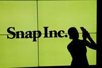 FILE PHOTO: FILE PHOTO: A woman stands in front of the logo of Snap Inc on the floor of the New York Stock Exchange (NYSE) in New York City, NY, U.S. March 2, 2017. REUTERS/Lucas Jackson/File Photo/File Photo