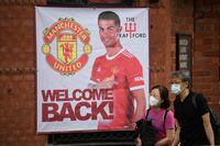 Fans walk past a banner featuring Manchester United's new signing Cristiano Ronaldo at Old Trafford stadium in Manchester, northwest England on September 10, 2021. (Photo by Oli SCARFF / AFP) (Photo by OLI SCARFF/AFP via Getty Images)