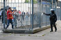 PARIS, FRANCE - MAY 28: Police spray tear gas at Liverpool fans outside the stadium prior to the UEFA Champions League final match between Liverpool FC and Real Madrid at Stade de France on May 28, 2022 in Paris, France. (Photo by Matthias Hangst/Getty Images)