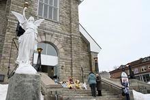 People gather among tributes left on the steps of the church in Amqui., Que., Tuesday, March 14, 2023 in Amqui, Que.&nbsp;A memorial mass will be held this evening in the Quebec town where two people were killed and nine injured when a pickup truck crashed into pedestrians. THE&nbsp;CANADIAN PRESS/Jacques Boissinot