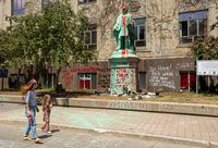 A woman and child walk past the shoes placed at the base of the Egerton Ryerson statue at Ryerson University in Toronto on Tuesday June 1, 2021. The statue was covered in paint by those protesting the discovery of a children's remains at the site of a former residential school in Kamloops. THE CANADIAN PRESS/Frank Gunn