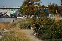 A man reads a book while sitting on a bench on the False Creek seawall in Vancouver, B.C., Thursday, Oct. 13, 2022. THE CANADIAN PRESS/Darryl Dyck