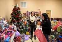 Crystal Perry, left, a mother of four and a former employee of ServiCom, laughs while choosing toys for her children with Salvation Army employee Amber Wareham in Sydney, N.S. on Dec. 20, 2018.