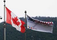 Canadian and LNG Canada flags fly outside of the company's office in Kitimat, British Columbia, Canada, on Friday, June 5, 2015. Canadian stocks rose a second day as commodities producers rallied after the price of oil climbed to the highest level this year while gold and copper led metals higher. Photographer: Ben Nelms/Bloomberg