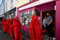 Shopkeepers look out as Red Brigade activists attend an Extinction Rebellion demonstration in Falmouth, during the G7 summit in Cornwall, Britain, June 12, 2021. REUTERS/Toby Melville