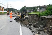 Crews begin repairs to a washed-out section of Highway 170 in Rivière-Éternité, Que., Sunday, July 2, 2023. The search for two people swept away by a landslide in Quebec's Saguenay-Lac-St-Jean region is stretching into a third day. THE CANADIAN PRESS/Jacques Boissinot