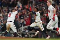 Atlanta Braves' Ozzie Albies, left, celebrates with Atlanta Braves' Eddie Rosario (8) after scoring the winning run on an RBI single by Atlanta Braves' Austin Riley in the ninth inning in Game 1 of baseball's National League Championship Series against the Los Angeles Dodgers Saturday, Oct. 16, 2021, in Atlanta. The Braves defeated the Dodgers 3-2 to take game 1. (AP Photo/Brynn Anderson)