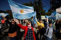 People hold Argentine flags as farmers ride their vehicles to protest new export taxes on farm goods applied by President Alberto Fernandez's administration, in Buenos Aires, Argentina April 23, 2022. REUTERS/Agustin Marcarian