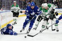 Toronto Maple Leafs forward Tyler Bertuzzi (59) reaches for the puck as forward William Nylander (88) and Dallas Stars forward Tyler Seguin (91) battle during second period NHL hockey action in Toronto on Wednesday, February 7, 2024. THE CANADIAN PRESS/Nathan Denette