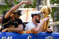 Otto Porter Jr. (L) and Klay Thompson hold a trophy as they wave from a double decker bus while basketball fans cheer during the Golden State Warriors NBA Championship victory parade along Market Street on June 20, 2022 in San Francisco, California. - Tens of thousands of fans poured onto the streets of San Francisco on Monday to salute the victorious Golden State Warriors as the team celebrated its fourth NBA championship in eight seasons with an open-top bus parade. (Photo by Patrick T. FALLON / AFP) (Photo by PATRICK T. FALLON/AFP via Getty Images)