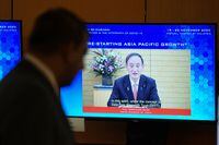 A man looks at a screen showing Japan's Prime Minister Yoshihide Suga speaking during the virtual APEC CEO Dialogues 2020, at its command center in Kuala Lumpur, Malaysia November 20, 2020.