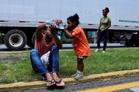 A man gives water to his daughter while taking part in a caravan as Venezuelans growing impatient of waiting for the humanitarian visa, cross the country to reach the United States, in Tapachula, in Chiapas state, Mexico June 24, 2022. REUTERS/Jose Torres