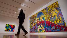 A reporter walks past 'Androgyny' by Norval Morrisseau (right) and 'Tweaker' by Lawrence Paul Yuxweluptun during a media tour of the Canadian and Indigenous Art: 1968 to Present at the National Gallery of Canada's contemporary art galleries Tuesday May 2, 2017 in Ottawa. THE CANADIAN PRESS/Adrian Wyld