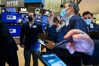 In this photo provided by the New York Stock Exchange, traders gather at a post on the floor, Friday, Jan. 21, 2022. Stocks wobbled between gains and losses on Wall Street Friday as major indexes head for another weekly loss. (Courtney Crow/New York Stock Exchange via AP)