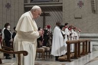 This photo taken and handout on April 16, 2022 shows Pope Francis (L) praying as seven newly-baptised from Cuba, Albania, USA and Italy (Rear R) hold their candle during the Easter Vigil mass at St. Peter's Basilica in The Vatican. (Photo by Handout / VATICAN MEDIA / AFP) / RESTRICTED TO EDITORIAL USE - MANDATORY CREDIT "AFP PHOTO / VATICAN MEDIA" - NO MARKETING - NO ADVERTISING CAMPAIGNS - DISTRIBUTED AS A SERVICE TO CLIENTS (Photo by HANDOUT/VATICAN MEDIA/AFP via Getty Images)