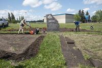 Ed Upland, left, and Ashley Sparvier, right, work to make a medicine wheel garden at the Ermineskin Residential School memorial in Maskwacis, Alberta on Monday, June 27, 2022. The garden will have quarters of red, green, yellow and white flowers with an orange perimeter. Amber Bracken for the Globe and Mail 