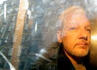 In this May 1, 2019, file photo, buildings are reflected in a window as WikiLeaks founder Julian Assange is taken from court, in London.