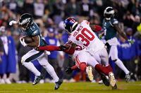 Philadelphia Eagles running back Kenneth Gainwell (14) runs with the ball as New York Giants cornerback Darnay Holmes (30) and safety Julian Love (20) try to stop him during the second half of an NFL divisional round playoff football game, Saturday, Jan. 21, 2023, in Philadelphia. (AP Photo/Matt Slocum)