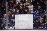 A fan holds up a sign referencing Vancouver Canucks general manager Jim Benning during a stoppage in play during the third period of an NHL hockey game against the Colorado Avalanche in Vancouver, on Wednesday, November 17, 2021. THE CANADIAN PRESS/Darryl Dyck