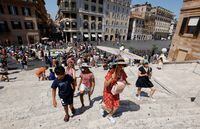 People shelter from the sun under an umbrella at the Spanish Steps during a heatwave across Italy, in Rome, July 10, 2023. REUTERS/Remo Casilli
