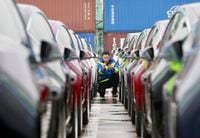 In this Feb. 22, 2019, photo, a port worker works among one of the first batches of Tesla Model 3 electric cars to be delivered to China at a port in Shanghai. In an unusual step, China’s ceremonial legislature is due to endorse a law meant to help end a bruising tariff war with Washington by discouraging officials from pressuring foreign companies to hand over technology. (Chinatopix via AP)