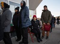 Deekshitha Jetta (sitting) and Rick Jallepalli (in green) pose for a photo while waiting in line November 3, 2023 at a visa processing office in Brampton.