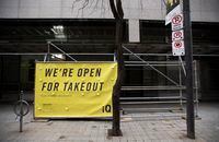 A large banner has been hung up outside the iQ restaurant in Toronto's Financial District, letting people know they're open for take out, on Jan 4 2021.