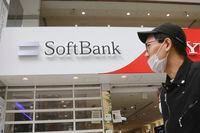 People walk by a SoftBank shop in Tokyo, Monday, Nov. 9, 2020. Japanese technology company SoftBank Group Corp. said Monday it restored its profitability in the last quarter as its investments improved in value. (AP Photo/Koji Sasahara)