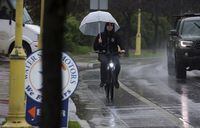 A cyclist tries to keep the rain at bay while pedaling on River Street in Santa Cruz, Calif., Wednesday, Jan. 11, 2023. (Shmuel Thaler/The Santa Cruz Sentinel via AP)