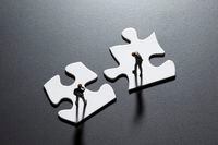San Diego, California, USA - July 25, 2011: Two Preiser businessman figurines standing on blank puzzle pieces illustrating the concepts of problem solving and negotiation. Shot in a studio setting.