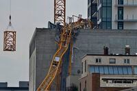A section (left) of the vertical column of a construction crane is lowered past the mangled section of the fallen boom in Kelowna, B.C., Wednesday, July 14, 2021, following a fatal collapse of the crane on Monday.THE CANADIAN PRESS/Desmond Murray