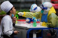 FILE PHOTO: A medical worker in a protective suit collects a swab sample from a chef for nucleic acid testing, during lockdown, amid the coronavirus disease (COVID-19) pandemic, in Shanghai, China, May 13, 2022. REUTERS/Aly Song/File Photo