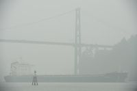 A ship comes through the smokey air as it goes under the Lion’s Gate Bridge in Vancouver on Sept. 14, 2020.