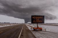 A sign signals the closure of Highway 16 as smoke billows up from a derailed Canadian Pacific Railway train near Guernsey, Sask., on Feb. 6, 2020.