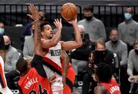 Portland Trail Blazers guard CJ McCollum, center, drives to the basket on Toronto Raptors guard Norman Powell, left, and forward OG Anunoby, right, during the second half of an NBA basketball game in Portland, Ore., on Jan. 11, 2021. The Blazers won 112-111.