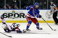 New York Rangers left wing Alexis Lafreniere (13) shoots past Columbus Blue Jackets defenseman Scott Harrington during the second period of an NHL hockey game Friday, Oct. 29, 2021, in New York. (AP Photo/Adam Hunger)