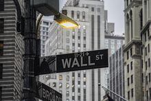 A street light brightens a Wall Street sign outside the New York Stock Exchange, Oct. 3.