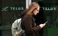 FILE PHOTO: A woman uses a mobile device while walking past a Telus store in Ottawa February 19, 2014.  REUTERS/Chris Wattie/File Photo